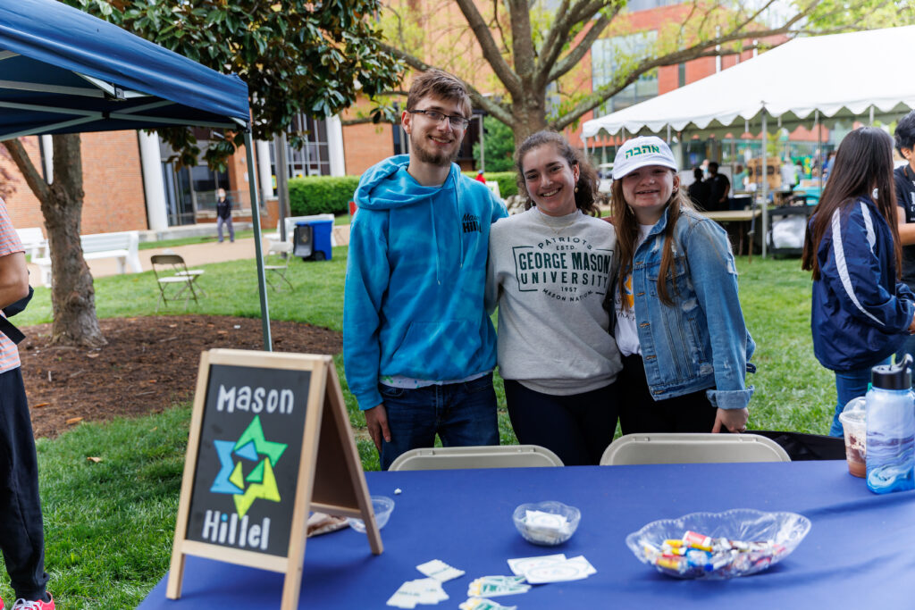 Students pose behind a table for Mason Hillel