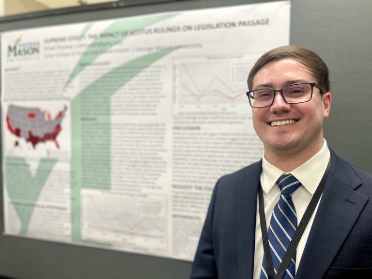 Ethan stands in front of his research poster at the conference