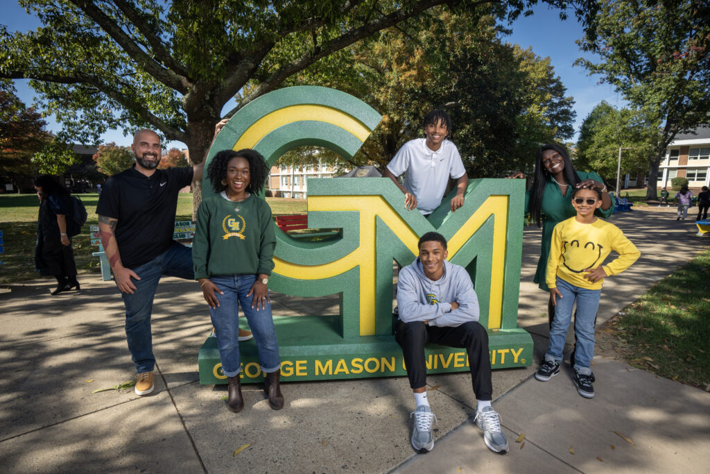 Family posing in front of the George Mason University logo.